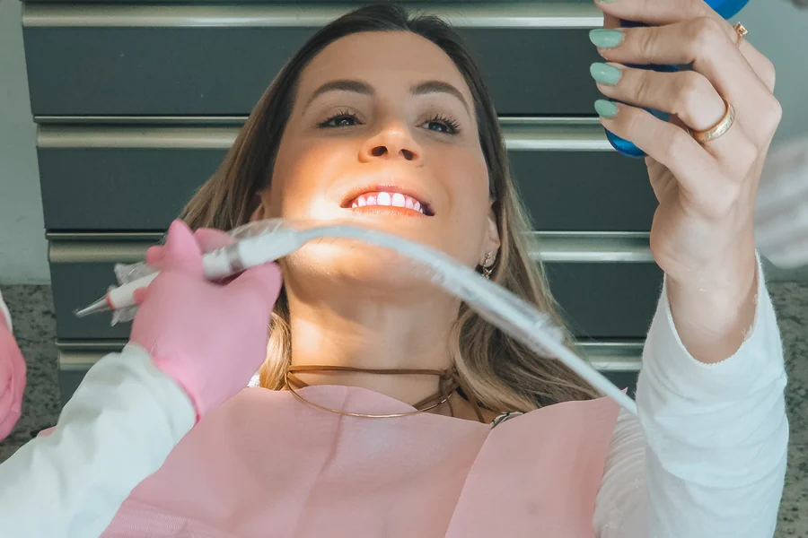 Paciente sorrindo ao ver o resultado do tratamento no espelho