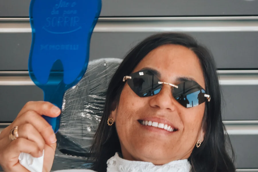 Paciente sorrindo com o espelho após atendimento odontológico