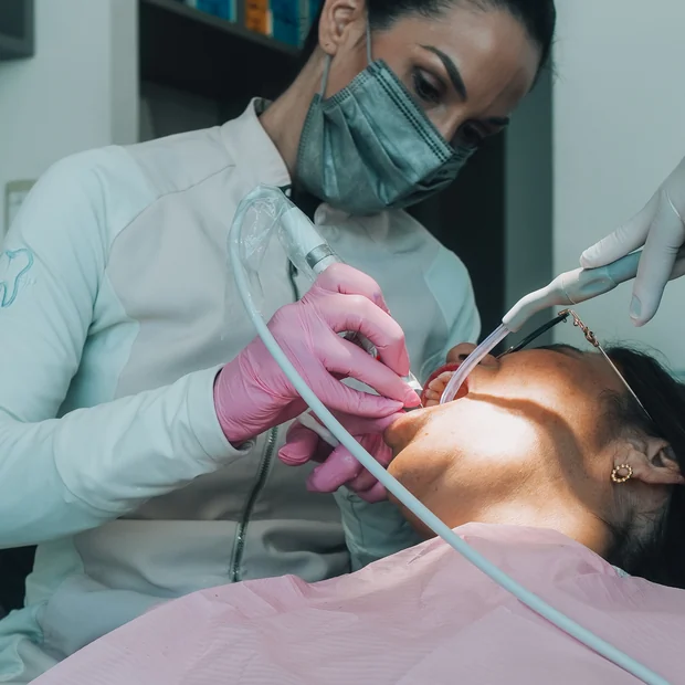 Procedimento clínico com fotopolimerizador durante atendimento odontológico